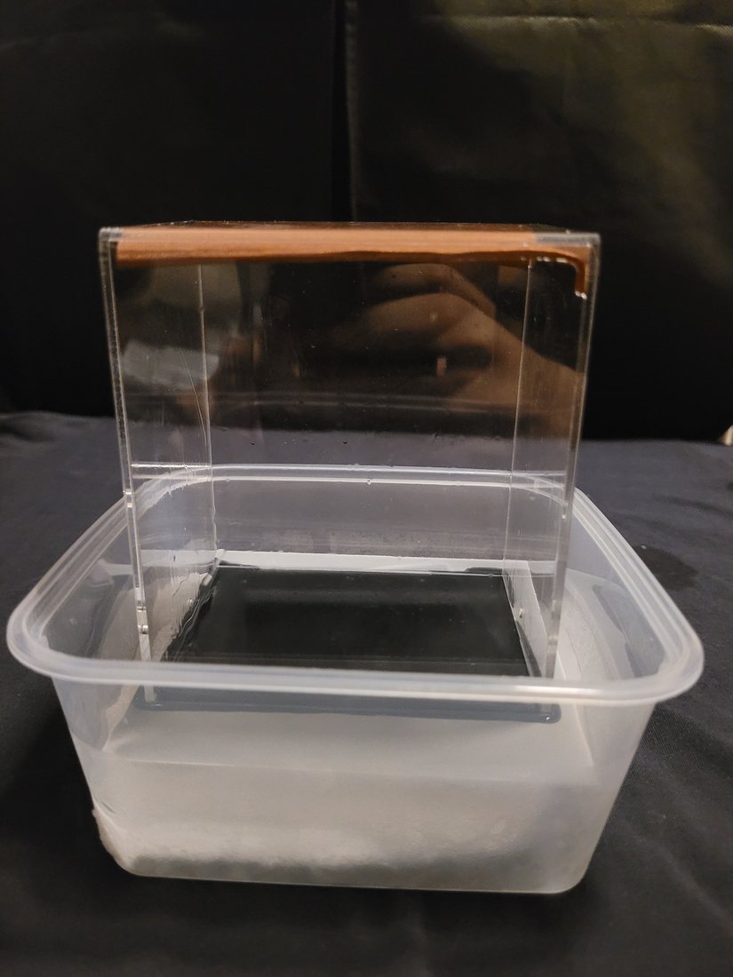 Overhead view of the chamber components laid out: sealed acrylic box, torch, isopropanol bottle, black plate and container.